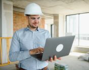 Male architect working on laptop at construction site