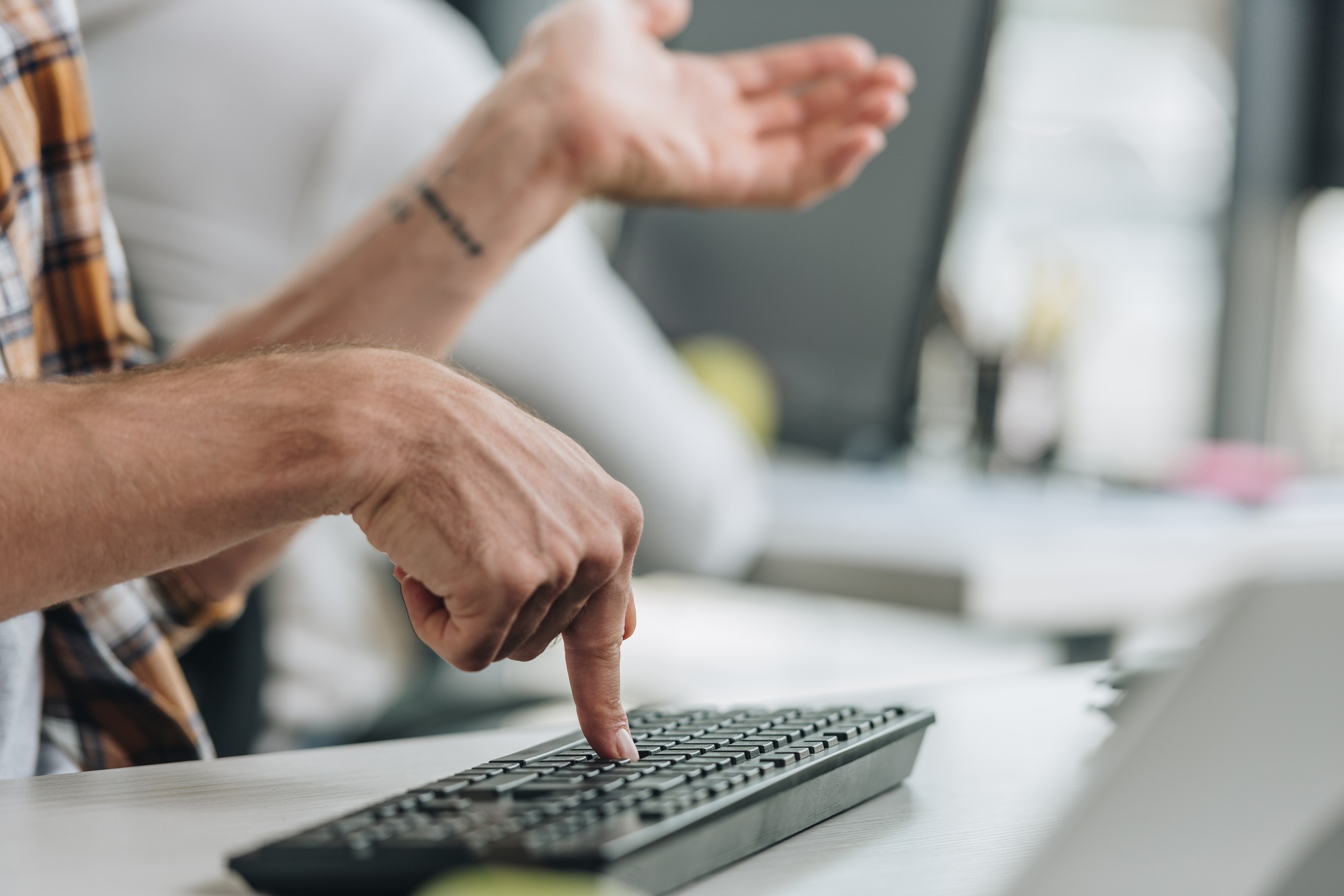 cropped view of programmer gesturing while pressing key on keyboard
