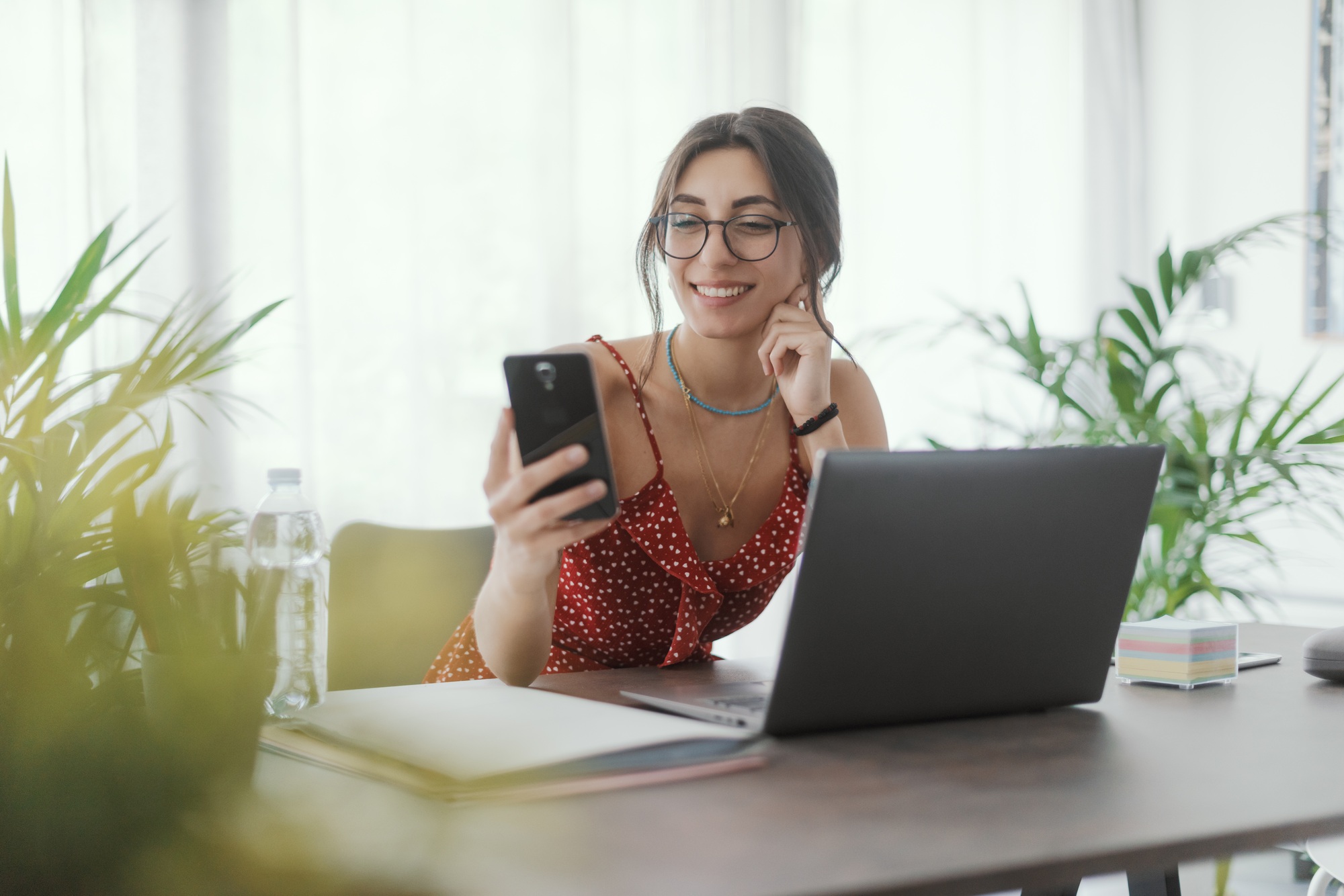 Young woman sitting at desk and using her smartphone